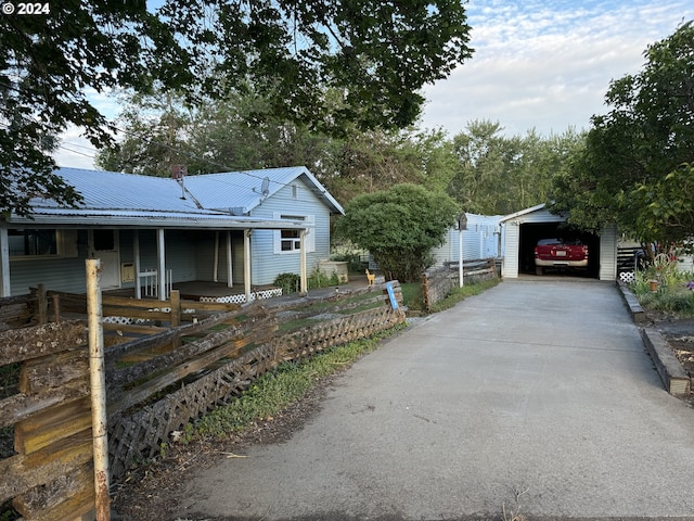 view of front facade featuring a porch, metal roof, fence, a garage, and driveway