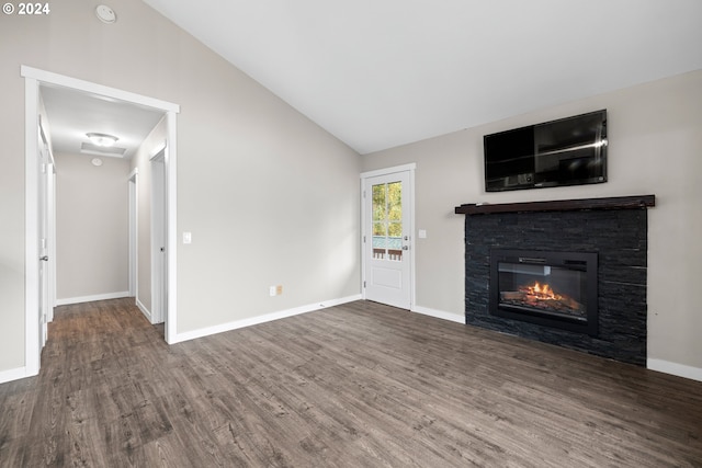 unfurnished living room with lofted ceiling, dark wood-type flooring, and a stone fireplace