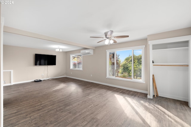 unfurnished living room featuring a wall unit AC, dark hardwood / wood-style floors, and ceiling fan