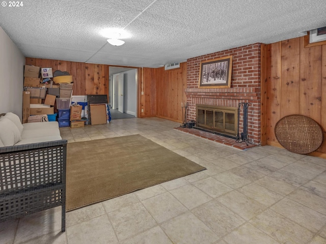 living room featuring a textured ceiling, a brick fireplace, and wood walls