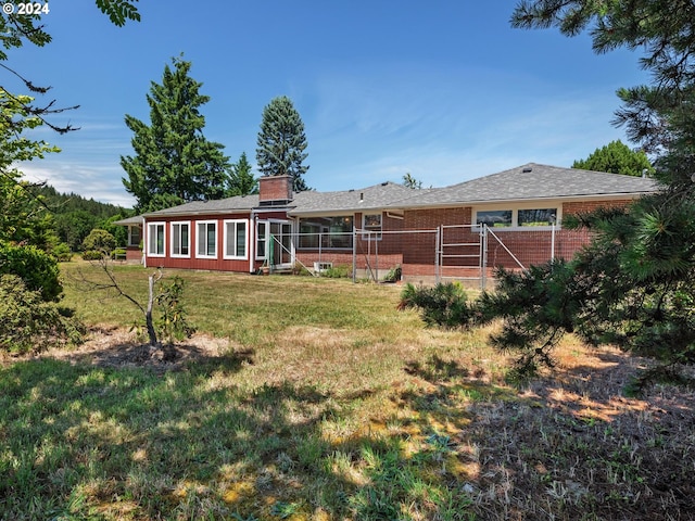 rear view of property featuring a sunroom and a lawn