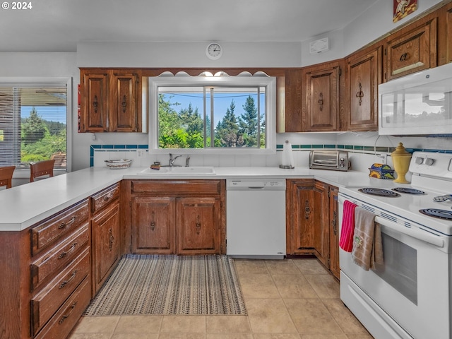 kitchen with decorative backsplash, light tile patterned floors, white appliances, and sink