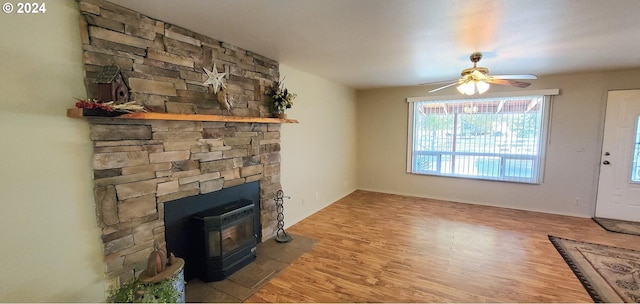 living room featuring a wood stove, hardwood / wood-style floors, and ceiling fan