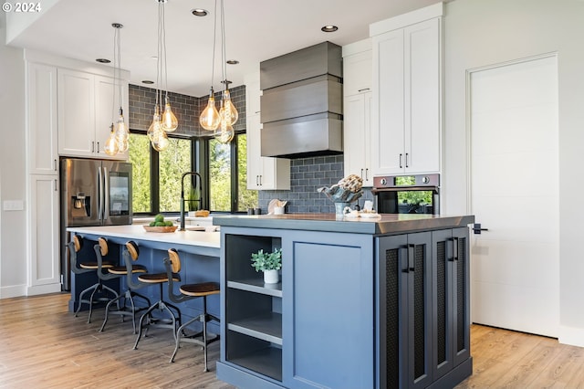 kitchen with hanging light fixtures, white cabinetry, a center island with sink, and stainless steel appliances