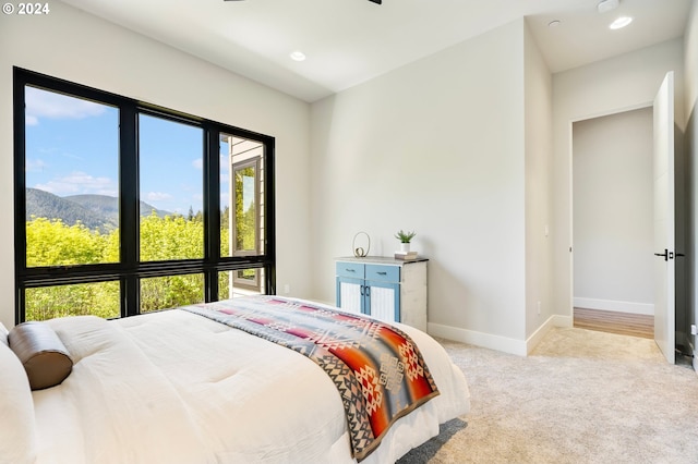 bedroom featuring multiple windows, light carpet, and a mountain view