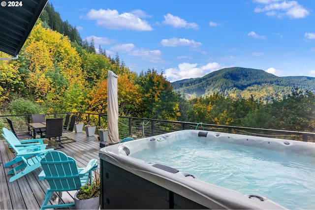 view of pool with a deck with mountain view and a hot tub