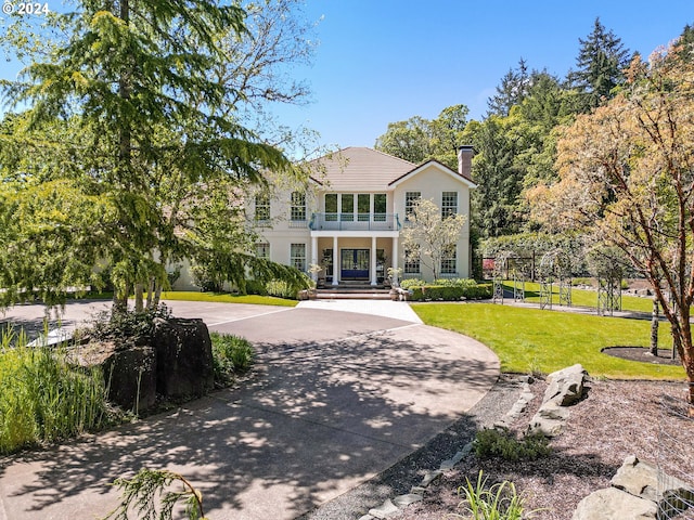 view of front of property featuring a balcony and a front yard