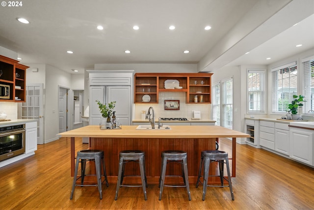 kitchen featuring stainless steel appliances, light hardwood / wood-style floors, a kitchen bar, and sink