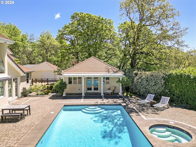 view of swimming pool featuring an outdoor structure, an in ground hot tub, and a patio area