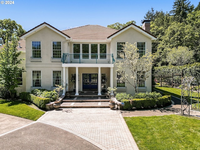 view of front facade with a balcony and a front lawn