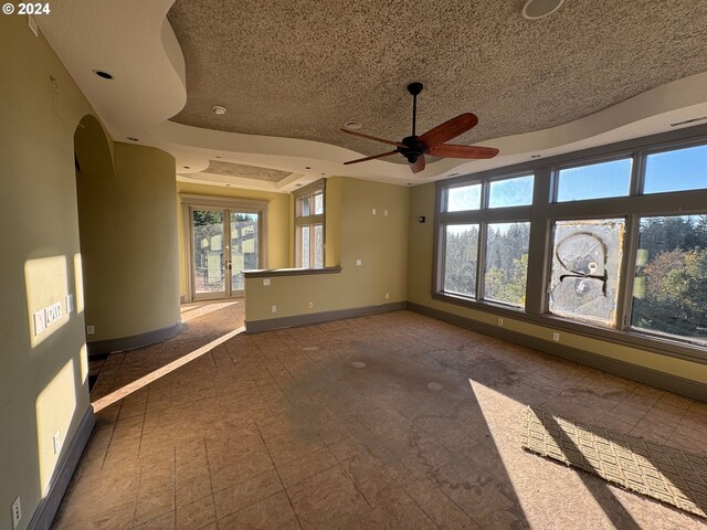 empty room featuring a tray ceiling, a textured ceiling, and ceiling fan