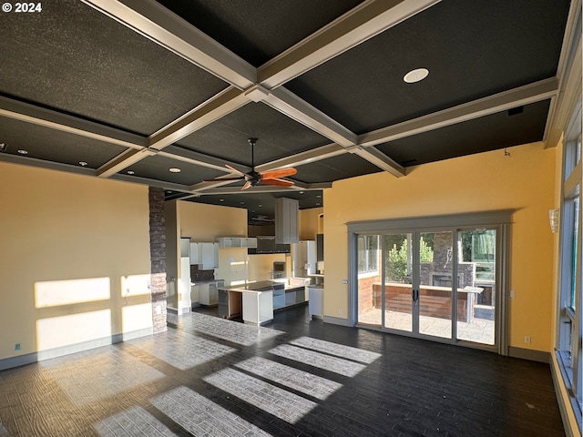 kitchen featuring ceiling fan, beam ceiling, a kitchen island with sink, coffered ceiling, and a breakfast bar