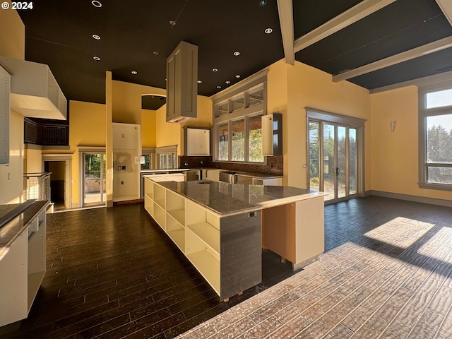 kitchen with stone countertops, dark hardwood / wood-style floors, beam ceiling, and a wealth of natural light