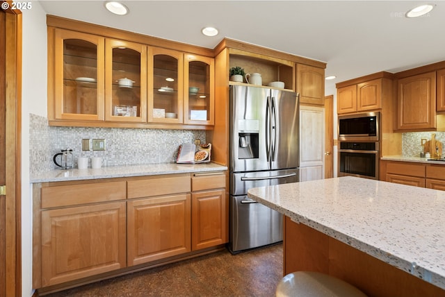 kitchen featuring appliances with stainless steel finishes, light stone countertops, and decorative backsplash