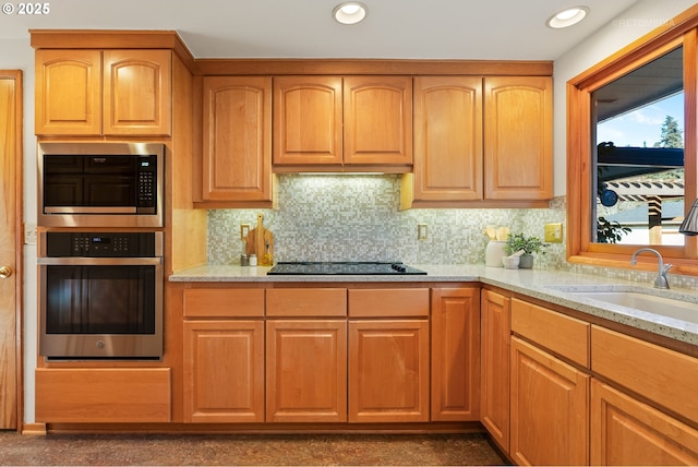 kitchen with light stone counters, sink, tasteful backsplash, and stainless steel appliances