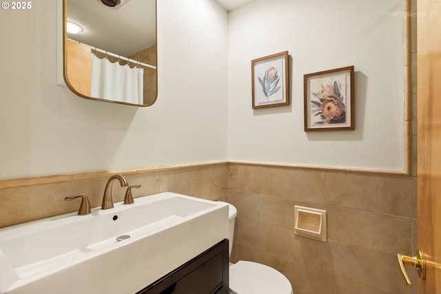 bathroom with vanity, toilet, and tile walls