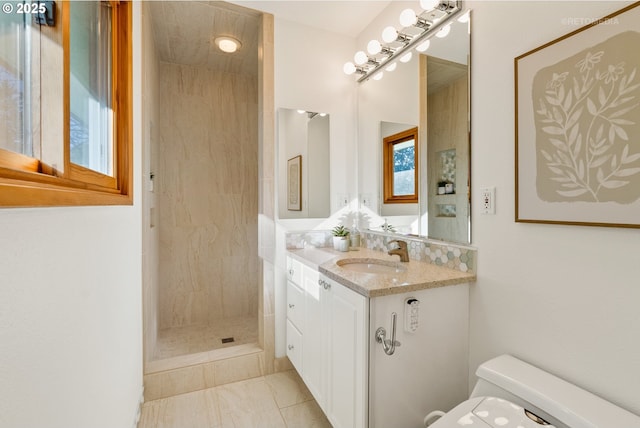 bathroom featuring vanity, tiled shower, and toilet