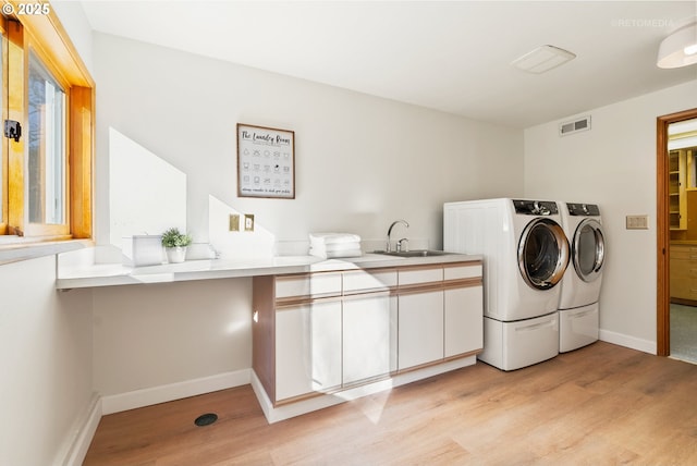 laundry room featuring sink, cabinets, light hardwood / wood-style floors, and washer and dryer