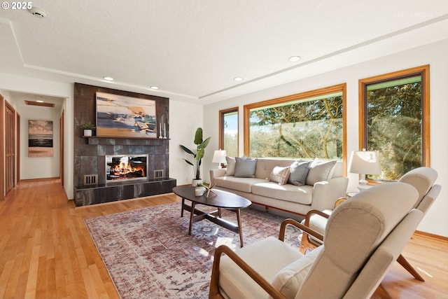 living room featuring a fireplace, a textured ceiling, and light wood-type flooring