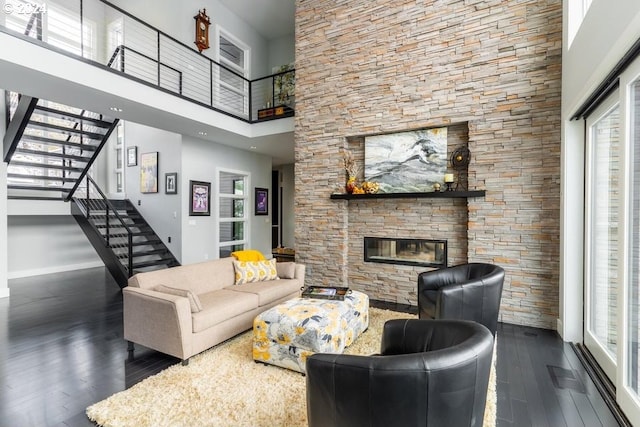 3425 NW Fairway Heights Dr, Bend, OR 97703 - living area featuring wood finished floors, a stone fireplace, stairway, a towering ceiling, and baseboards