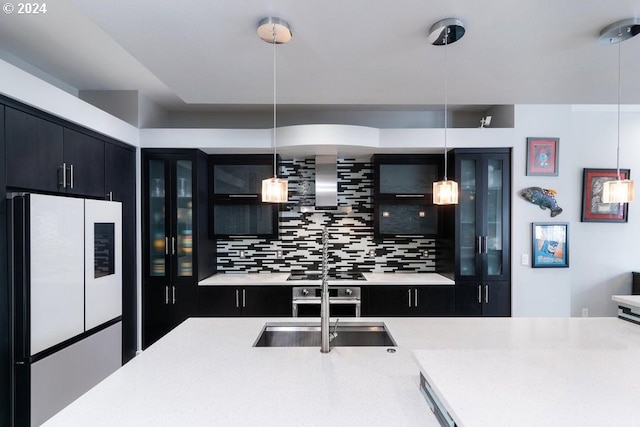 kitchen featuring white refrigerator, decorative light fixtures, tasteful backsplash, and dark cabinets