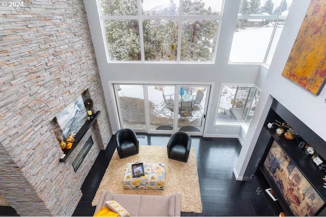 3425 NW Fairway Heights Dr, Bend, OR 97703 - living room with a stone fireplace, a high ceiling, dark wood-type flooring, and baseboards