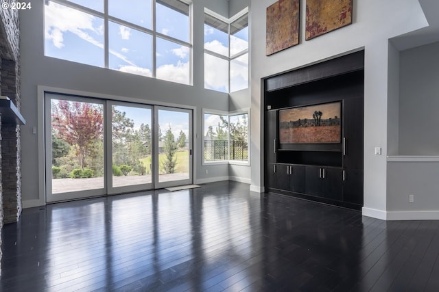 living room featuring dark wood finished floors, baseboards, and a towering ceiling