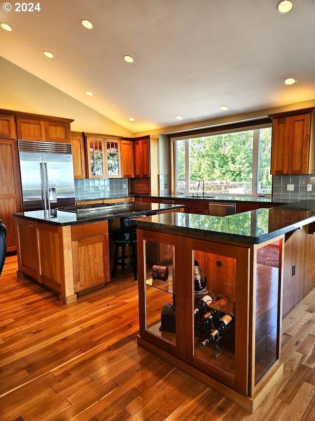 kitchen with hardwood / wood-style floors, appliances with stainless steel finishes, a kitchen island, and decorative backsplash