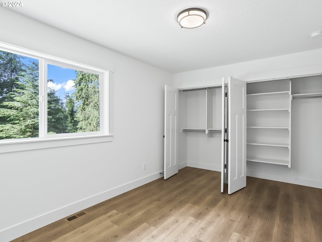 unfurnished bedroom with hardwood / wood-style flooring and two closets