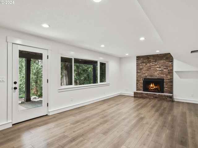 unfurnished living room featuring a brick fireplace and light hardwood / wood-style flooring