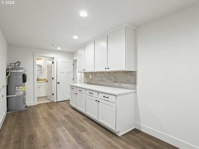 kitchen featuring white cabinets, secured water heater, light wood-type flooring, and decorative backsplash