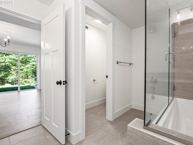 bathroom featuring shower with separate bathtub, a chandelier, and tile patterned flooring