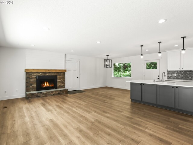 kitchen with sink, white cabinets, light hardwood / wood-style floors, and decorative light fixtures