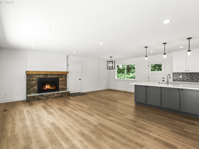 kitchen featuring light hardwood / wood-style flooring, sink, hanging light fixtures, and white cabinets