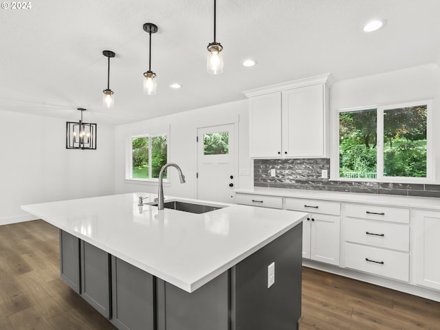 kitchen featuring white cabinetry, sink, an island with sink, and pendant lighting