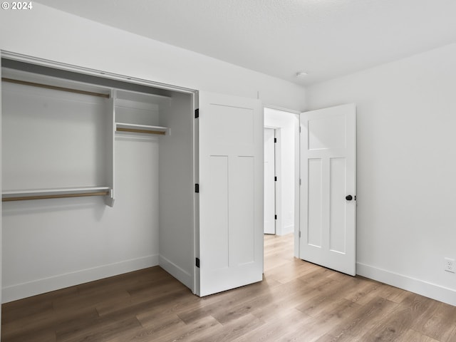 unfurnished bedroom featuring light wood-type flooring and a closet