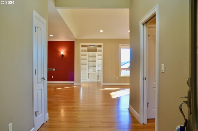 corridor featuring built in features and light hardwood / wood-style floors