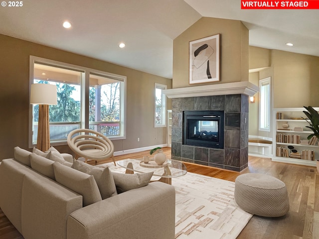 living room featuring lofted ceiling, hardwood / wood-style floors, and a tile fireplace