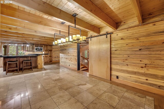 interior space featuring beamed ceiling, wooden walls, a barn door, and wood ceiling