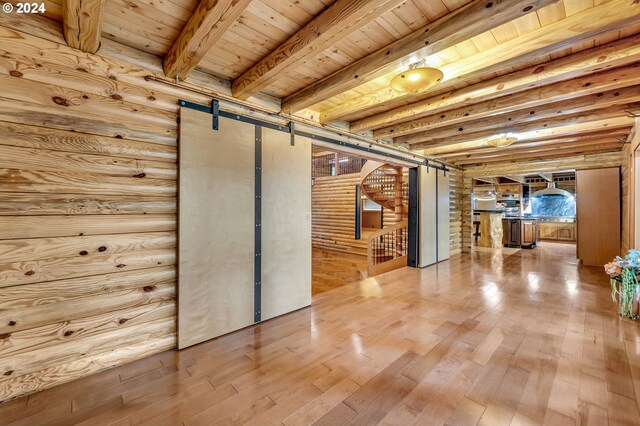 basement with light hardwood / wood-style floors, a barn door, and wood ceiling