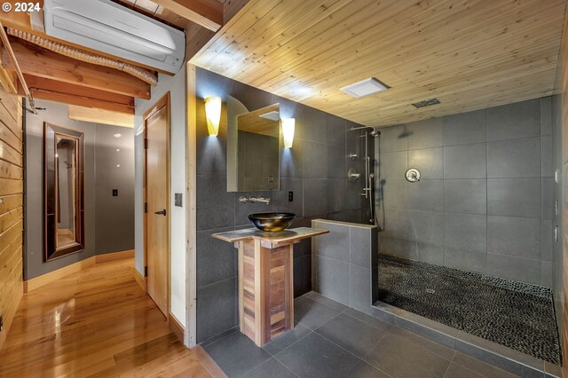 bathroom featuring vanity, a wall mounted AC, wood-type flooring, a shower, and tile walls