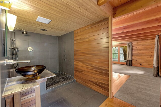 bathroom with vanity, wooden walls, a shower, wooden ceiling, and tile patterned flooring