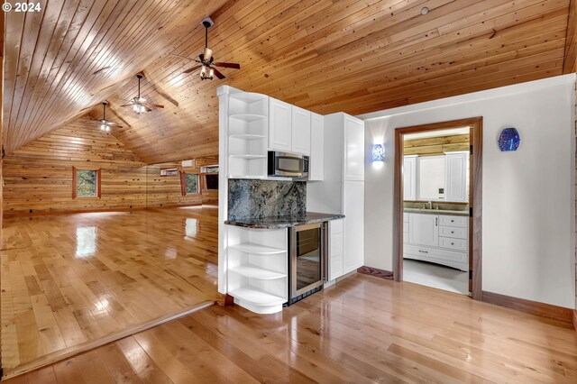 kitchen with light wood-type flooring, wooden ceiling, decorative light fixtures, wine cooler, and wooden walls