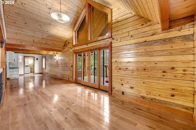 unfurnished living room featuring high vaulted ceiling, wooden walls, beamed ceiling, wood-type flooring, and wood ceiling