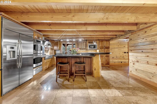 kitchen featuring wall chimney range hood, built in appliances, wooden walls, and wooden ceiling