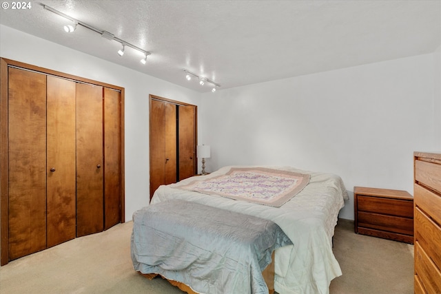 carpeted bedroom with multiple closets and a textured ceiling