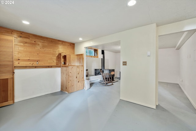 basement with a wood stove and wooden walls