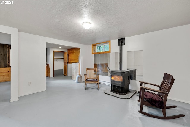 living area with concrete flooring, a textured ceiling, and a wood stove