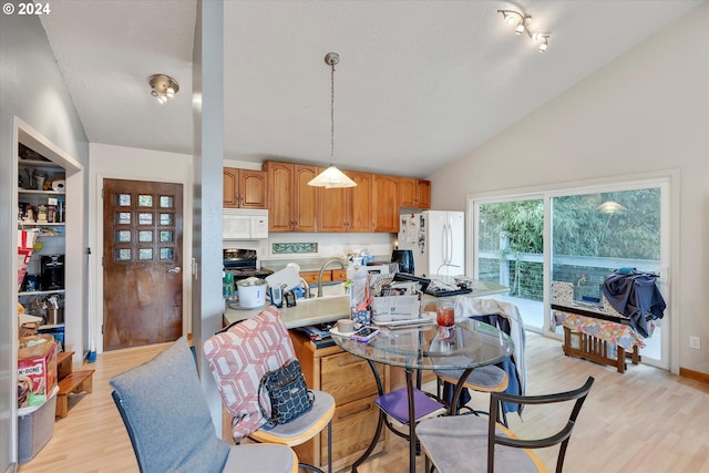 dining space featuring lofted ceiling, sink, and light wood-type flooring