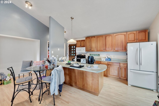 kitchen featuring white appliances, light wood-type flooring, a center island, hanging light fixtures, and vaulted ceiling